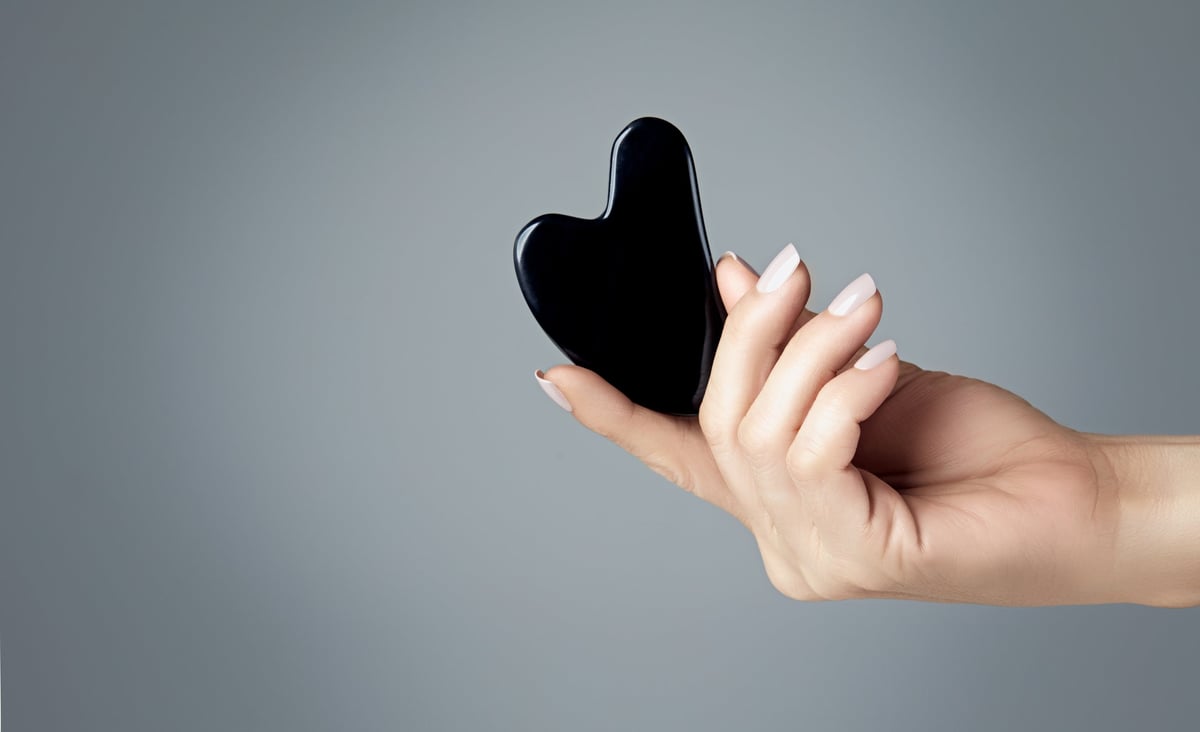 Gua sha tool being used on face for anti-aging facial massage treatment