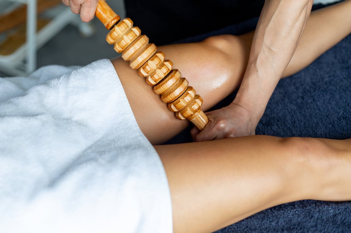 Maderotherapy massage treatment is performed on woman's legs by professional masseur in wellness spa center