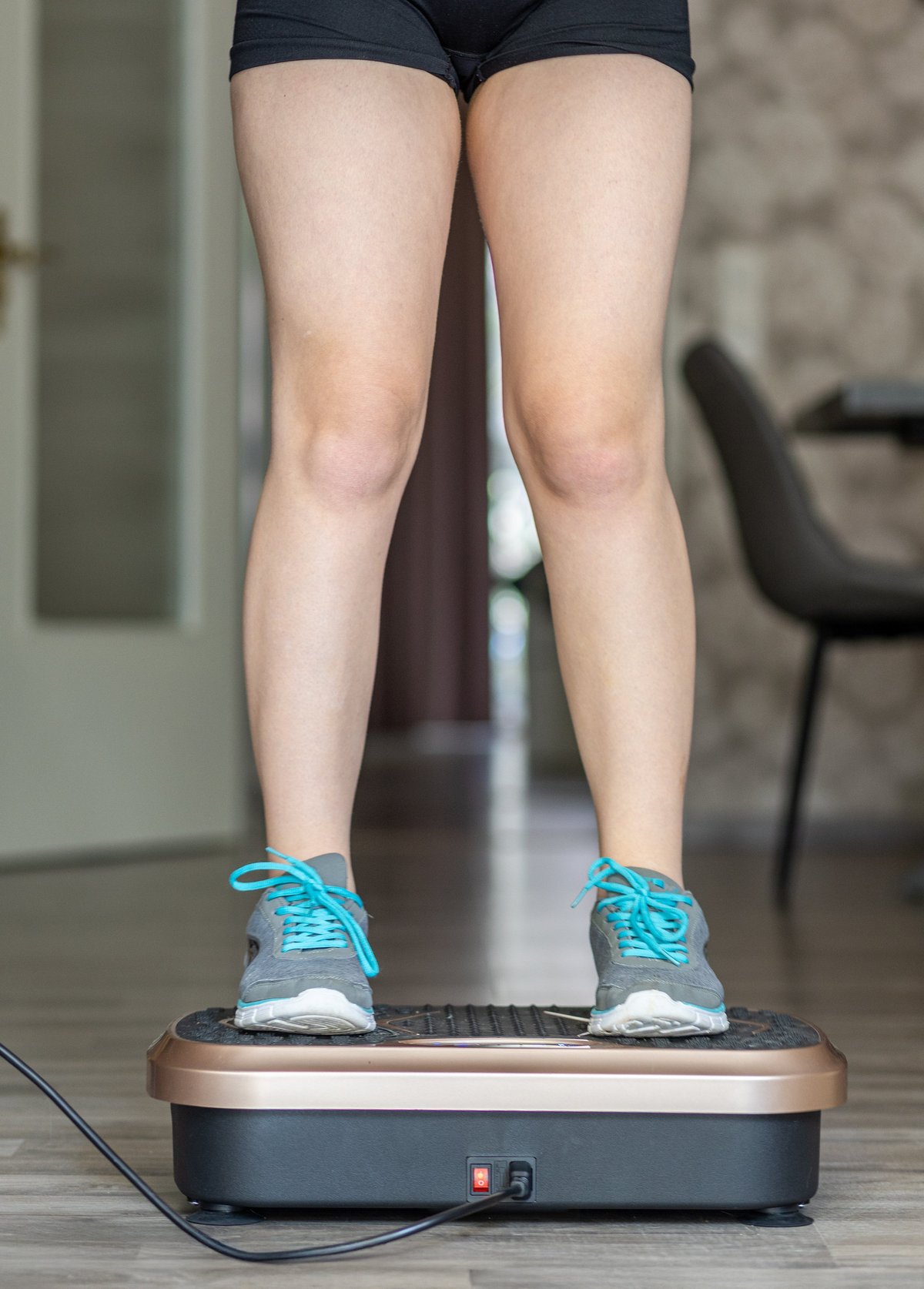 Person standing on vibration plate machine for wellness and circulation therapy