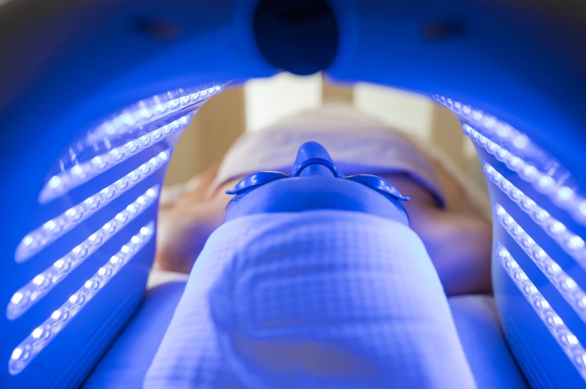 Young woman receiving blue LED light therapy treatment in beauty salon