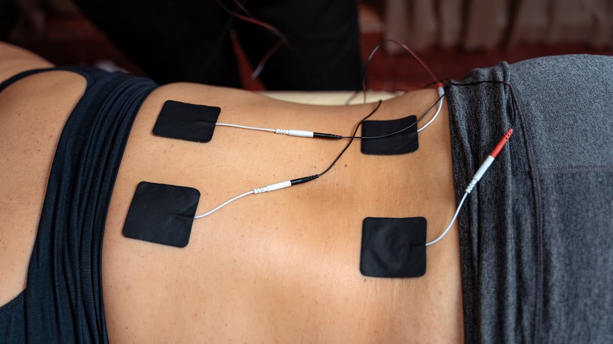 EMS electrical muscle stimulation therapy with electrode pads attached to back for muscle toning and definition