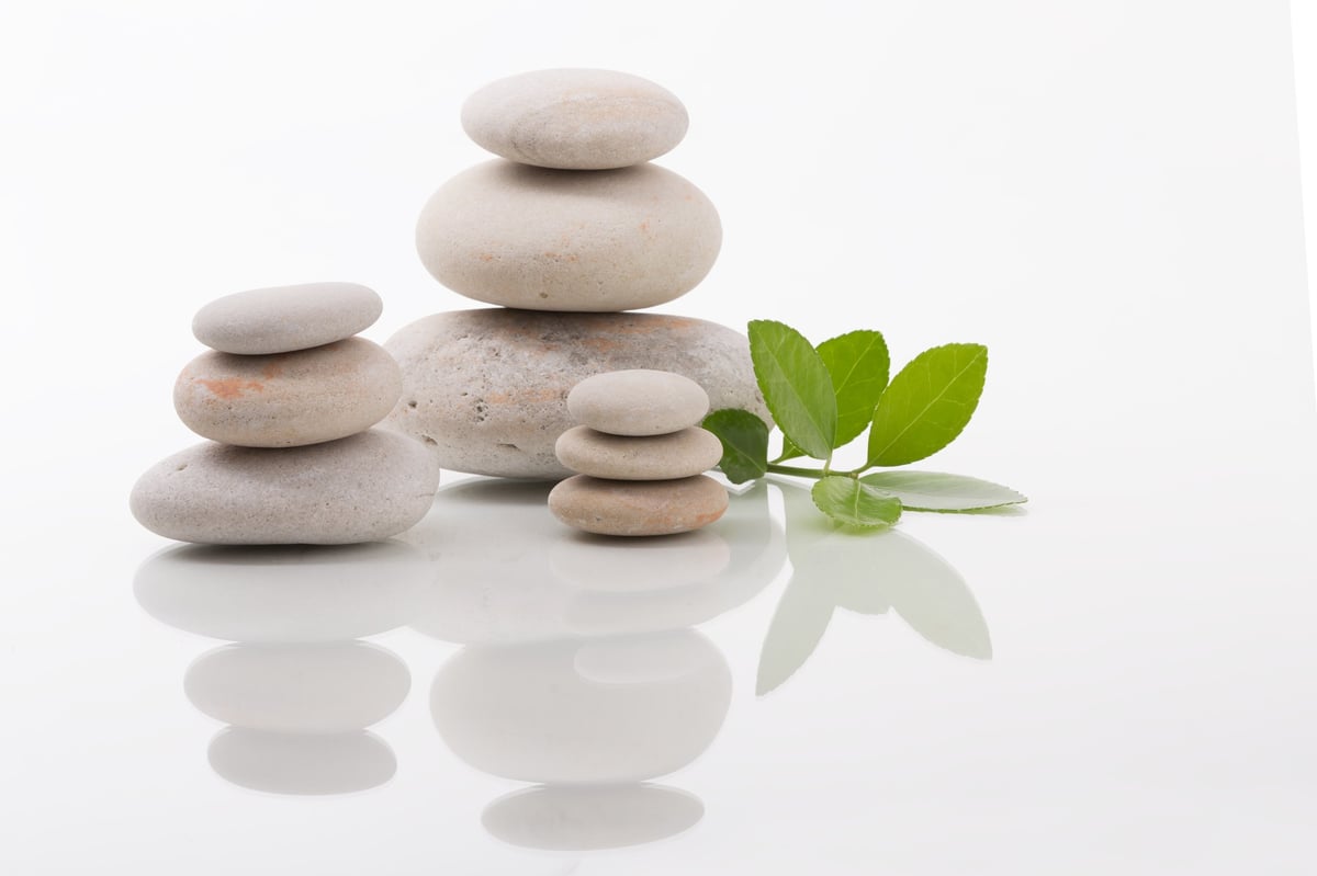 Balanced zen stones with green leaves on white surface creating zen harmony and wellness