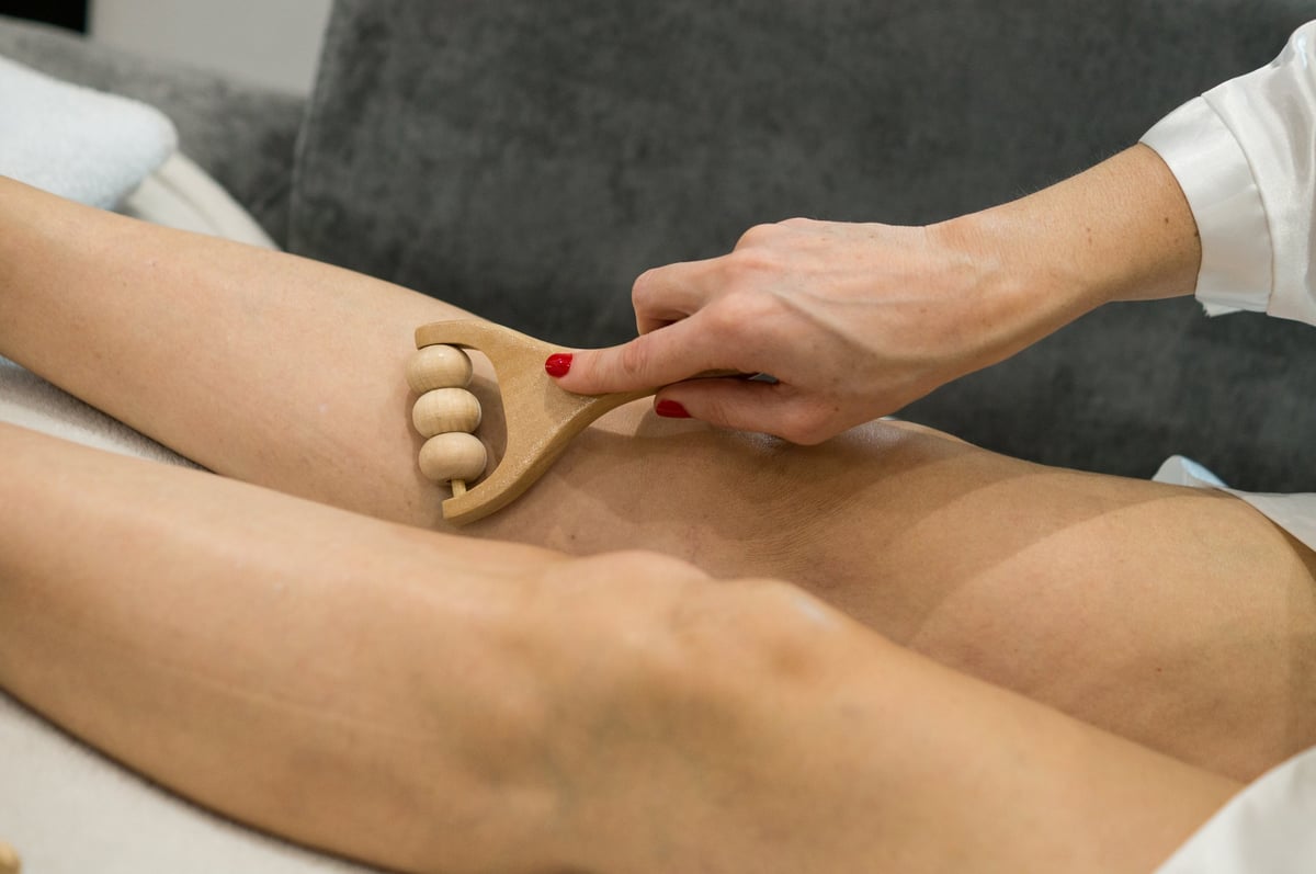 Wooden massage tool rolling over skin to stimulate blood flow and reduce appearance of imperfections
